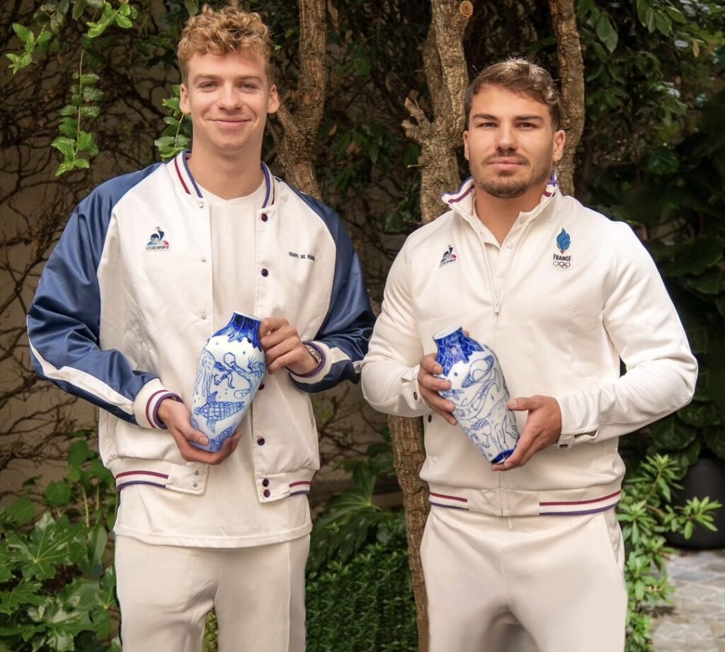 Léon Marchand et Antoine Dupont tenant les vases de Domitille Siergé dans leurs mains